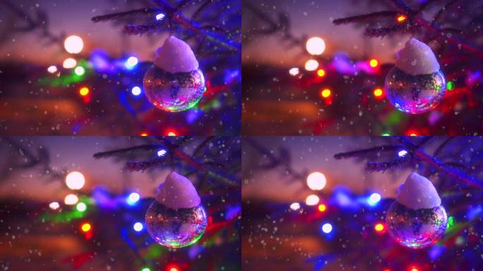 圣诞树的特写树枝，五颜六色的闪烁的灯光bokeh被飘落的雪包围