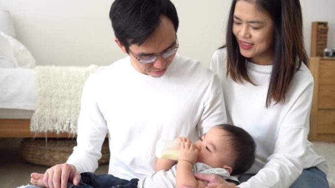 亚洲家庭的年轻父母在家中用奶瓶喂养男婴