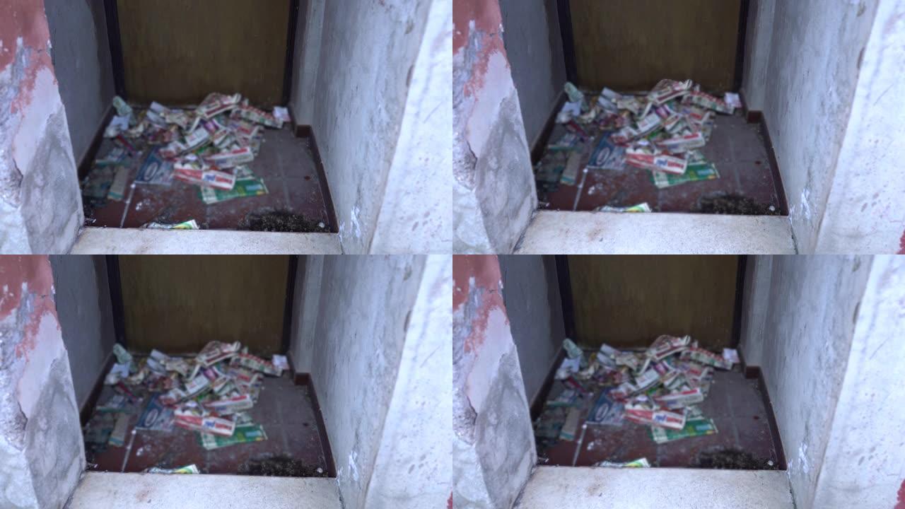 一堆旧脏纸躺在靠近居民楼门的路上，街上的垃圾场。垃圾，垃圾和废物的环境污染，人们的冷漠，破坏