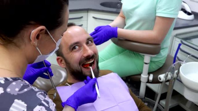 男性患者正在咀嚼特殊的牙科指示器，牙医正在检查它