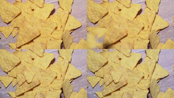玉米片落在木板上，特写。有害的墨西哥小吃，不健康的快餐。脆皮，咸黄色玉米三角形4k