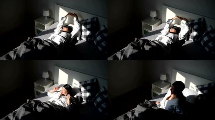 一个年轻女子醒来后坐在床上。阳光照在她的脸上。早上好