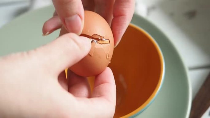 女厨师在碗里打碎一个生鸡蛋，做早餐炒鸡蛋。