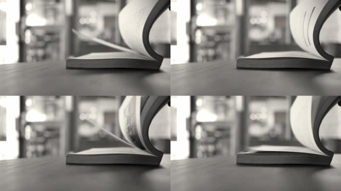 双手翻转放在咖啡馆木桌上的书页。