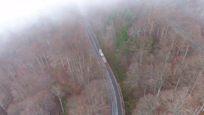 雾蒙蒙的秋日，重载卡车在山林上坡行驶，无人机景观