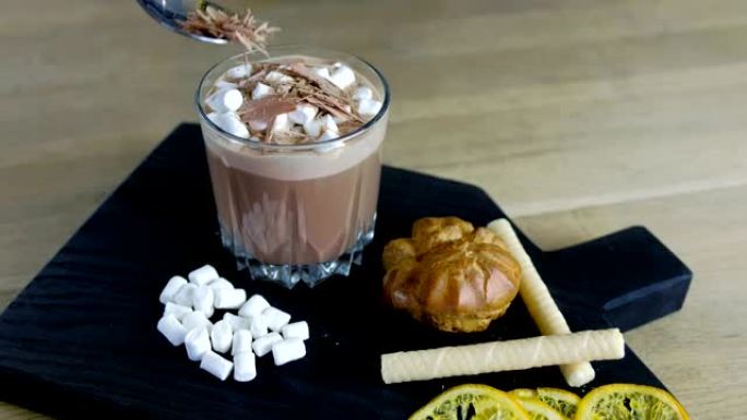 咖啡师将磨碎的巧克力撒在可可上，并用石杯中的棉花糖。煮可可。特写视图。