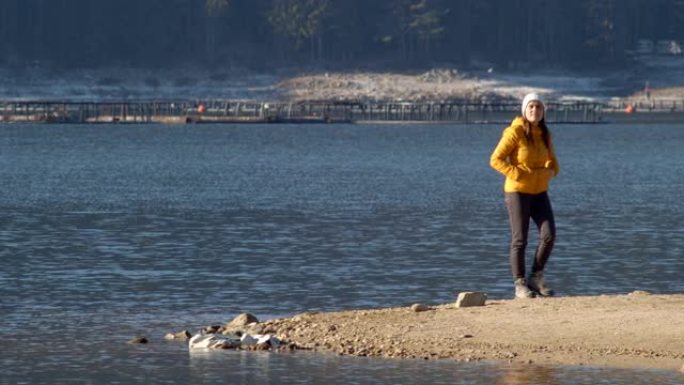 回归自然。独自旅行者在山湖岸边拍照。大自然中一个快乐的年轻女性游客。在阳光明媚的日子里享受户外。