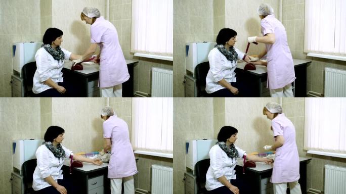 一名女性实验室助理从一名成年女性的静脉中抽取血液。高清