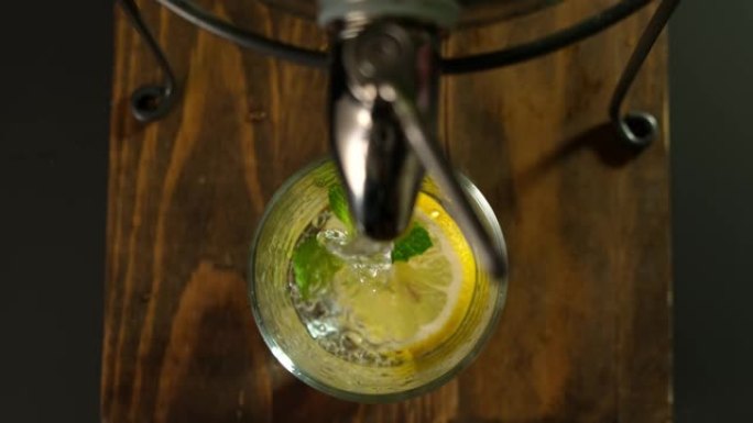 将健康的新鲜柠檬水与大水罐中的冰和薄荷倒入玻璃杯中。顶视图。