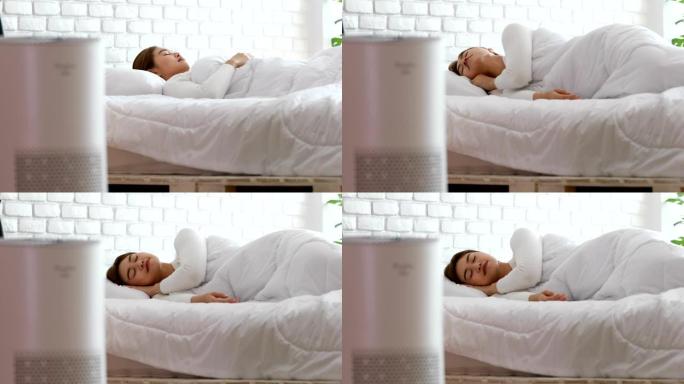女人在舒适的白色卧室里用空气净化器睡觉，用于过滤和清洁去除家庭中的灰尘PM2.5 HEPA，用于新鲜