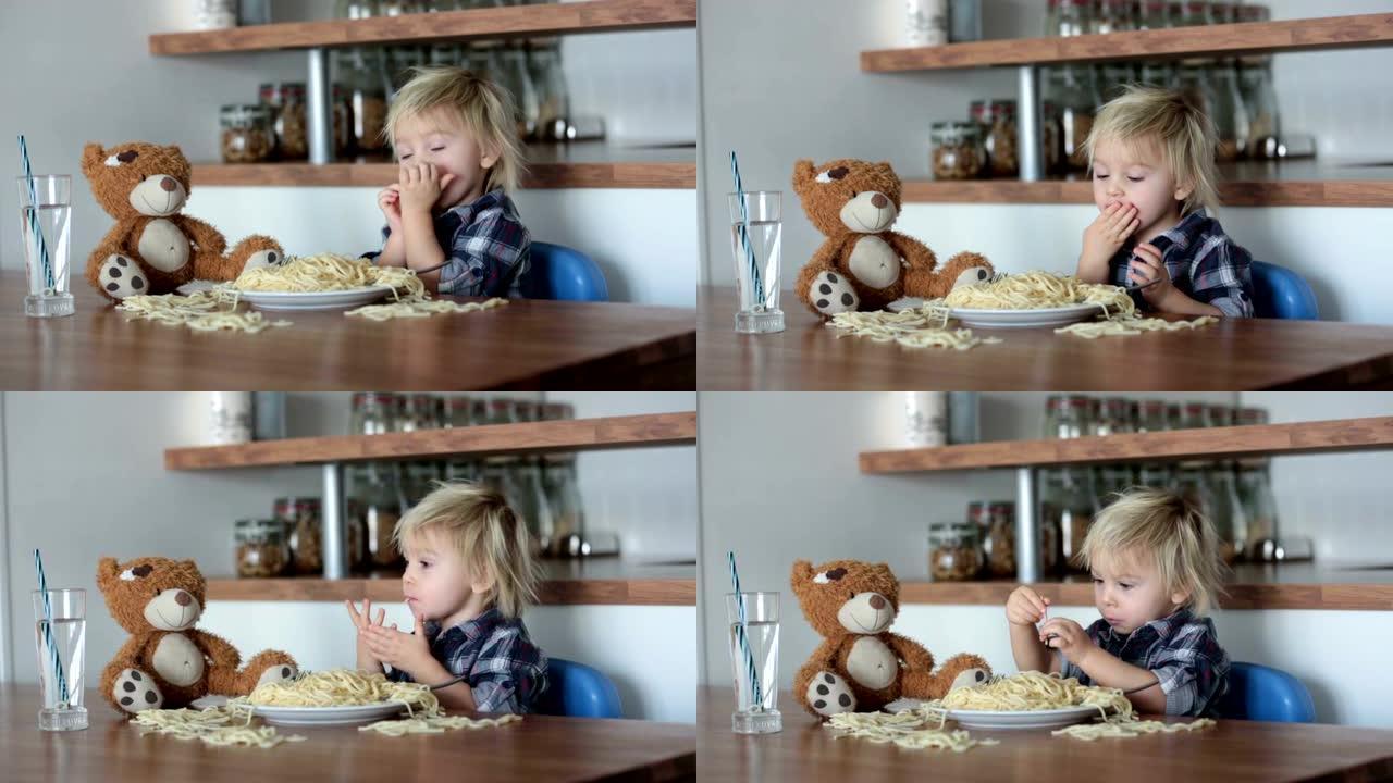 小男孩，蹒跚学步的孩子，午餐吃意大利面，做喂养泰迪熊的朋友