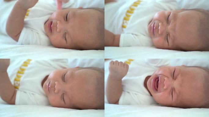 在家里床上哭泣的新生婴儿的特写镜头。饥饿的婴儿男孩哭着喝牛奶