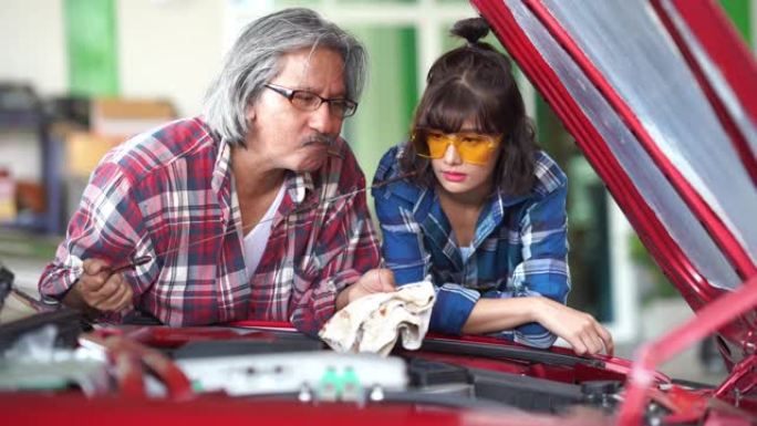 高级技师男子训练班为年轻技师女子检查车库中的机油
