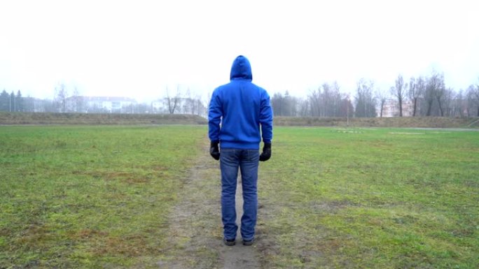 孤独的概念，一个人独自站在公园的户外，后视，戴着拳击手套，战斗生活，倾斜相机，底视视频