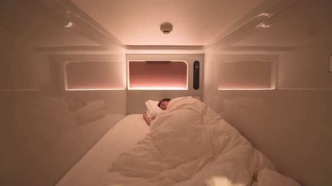 一个睡在胶囊旅馆里的人，日本。自助检疫，便宜的房间或隔离概念。