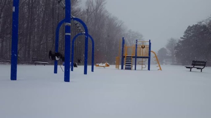 冬季降雪期间儿童游乐园。白天在地面上下雪的操场。