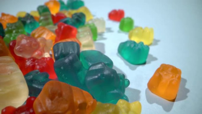 宏观特写广角滑动镜头含糖五颜六色美味甜软糖熊糖果堆在蓝色背景上