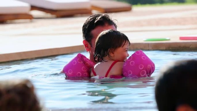 父亲和女儿在游泳池里玩耍，举起孩子