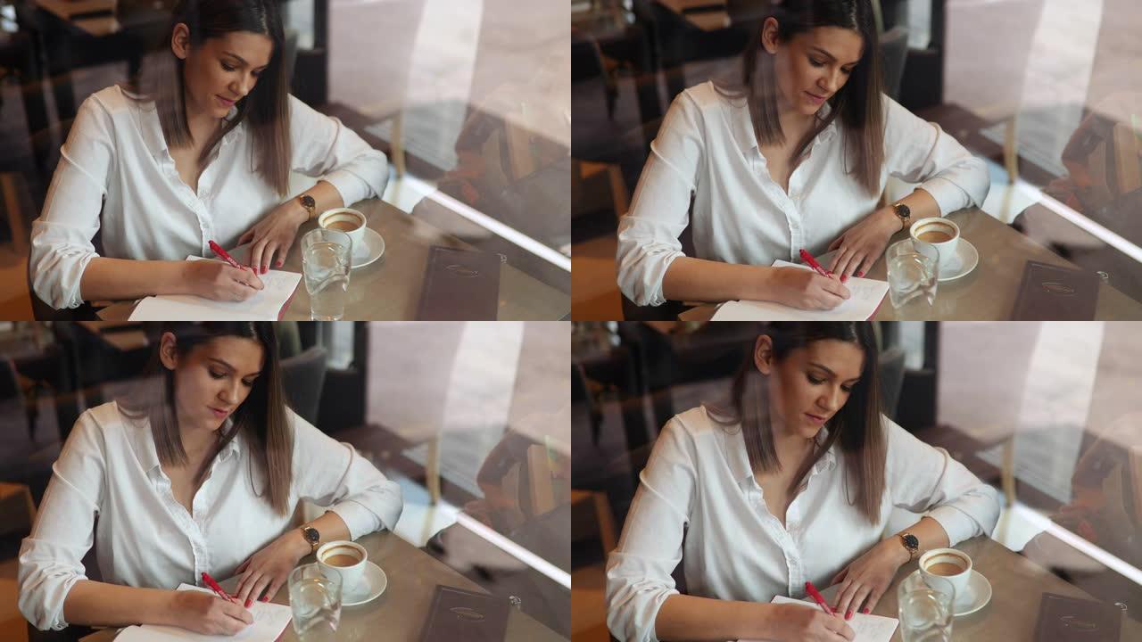 女作家坐在咖啡馆里，在笔记本上写笔记