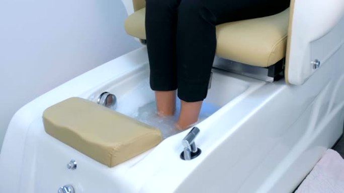 女人在水疗沙龙里泡脚，坐在修脚椅上，双腿特写。