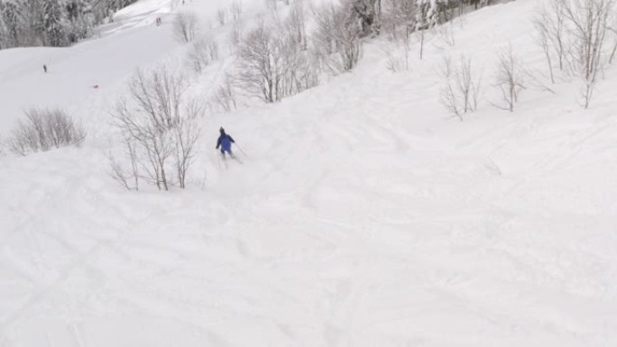滑雪者在冬季度假胜地白雪皑皑的山坡上骑自由车。鸟瞰滑雪者在雪场的山坡上行驶。从冬季运动和人员活动上方