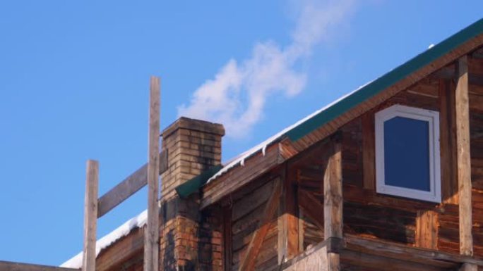 冬天，在蓝天下，木屋屋顶上的砖烟囱冒烟