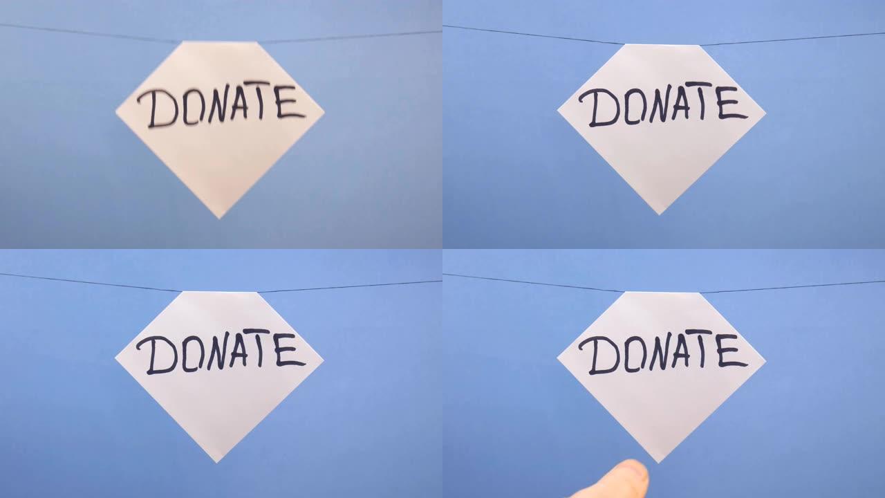 一名男子在蓝色背景上悬挂一张白纸，上面刻有黑色题词 “捐赠”