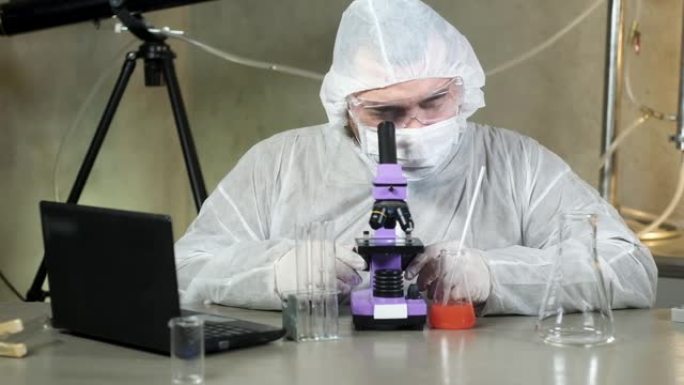 实验室的科学家在显微镜下观察并在笔记本电脑上打印数据。