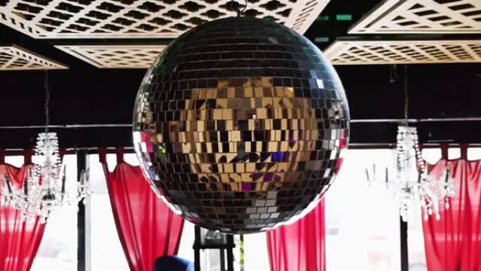 餐厅里的旋转镜迪斯科球。镜子迪斯科球对派对慢动作的影响。在派对上的一家俱乐部餐厅的木制天花板下旋转迪