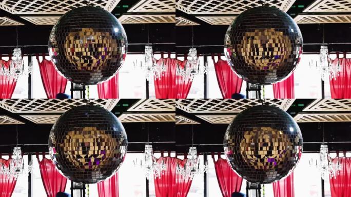 餐厅里的旋转镜迪斯科球。镜子迪斯科球对派对慢动作的影响。在派对上的一家俱乐部餐厅的木制天花板下旋转迪