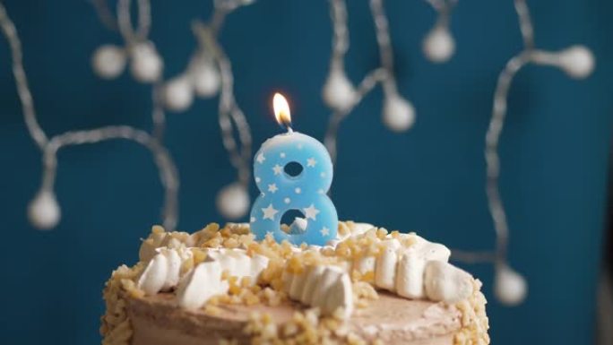 蓝色背景上有8个数字蜡烛的生日蛋糕。蜡烛吹灭了。慢动作和特写视图