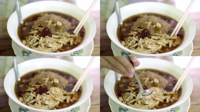 特写手用筷子捏吃泰国热面条。