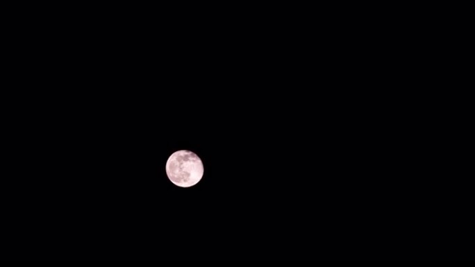 巨大的红色满月在黑色的夜空上运动。时间流逝