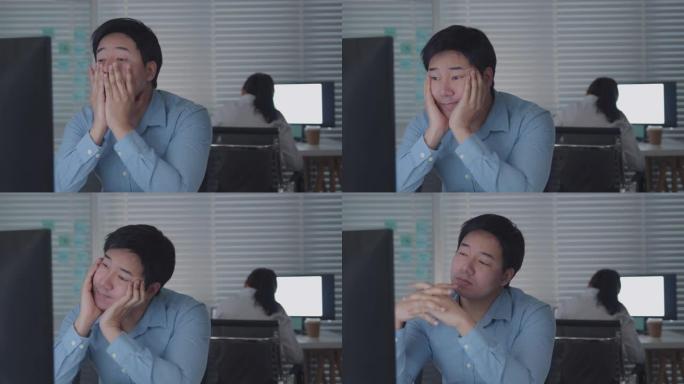 疲惫的亚洲男工在公司办公室里用台式电脑工作