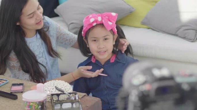 年轻的亚洲女性博主展示化妆和化妆品。女孩使用相机在家庭客厅录制vlog视频直播。商业在线影响者概念。