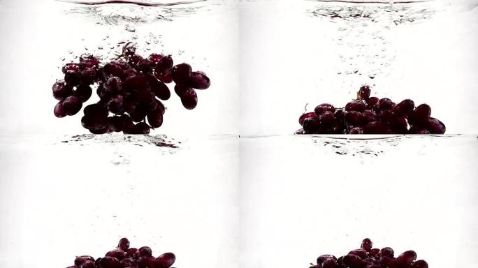 成熟的红葡萄落入带有气泡的纯净水中。慢动作白色背景上的葡萄浆果。