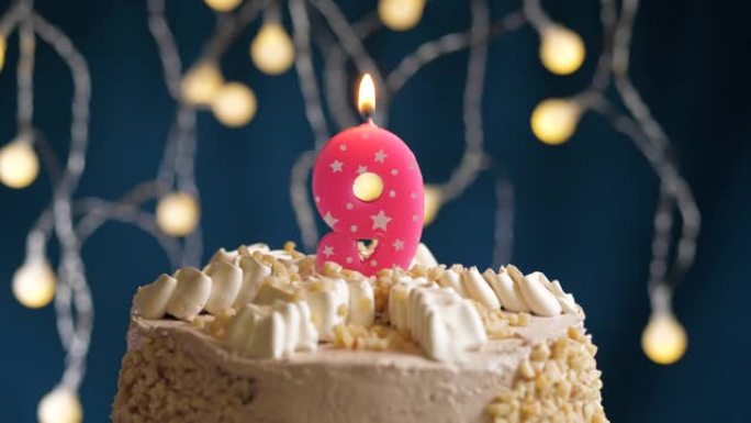 蓝色背景上有9号粉色蜡烛的生日蛋糕。蜡烛吹灭了。慢动作和特写视图