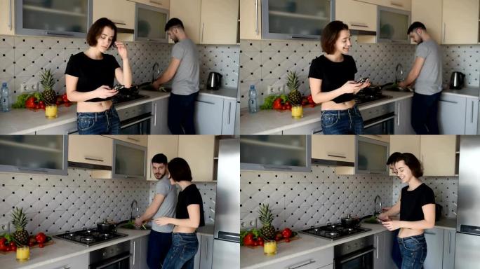 美丽的年轻夫妇在家里的厨房里烹饪健康食物时说话和微笑