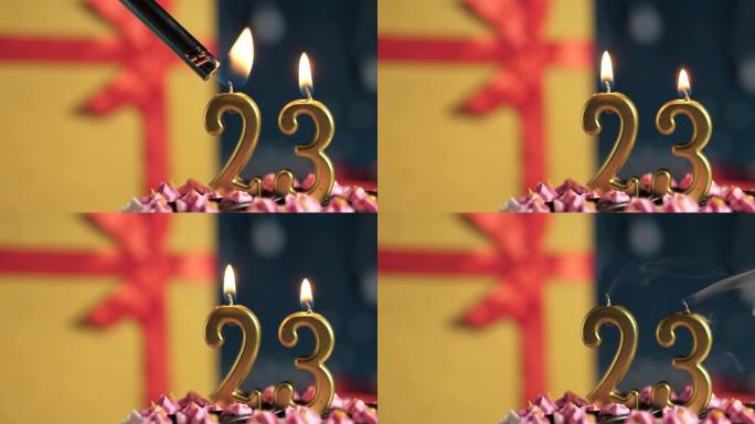 生日蛋糕编号23点灯燃烧的金色蜡烛，蓝色背景礼物黄色盒子用红丝带绑起来。特写和慢动作