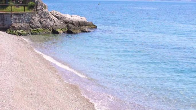 海滨海滩上的壮丽景色，蔚蓝的水，黄沙和照片角落的一块小石头。美丽的亚得里亚海海边，有黄白色的沙子和干