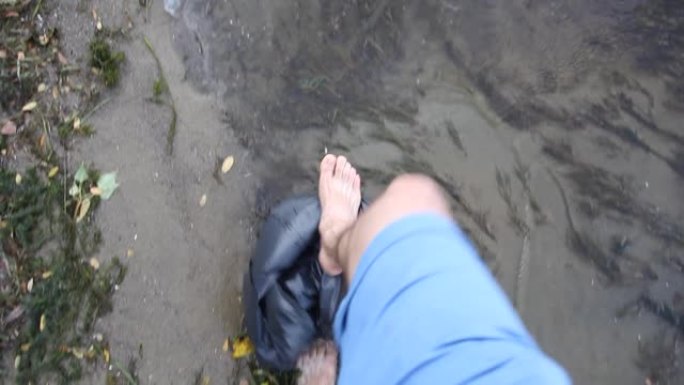 一个人在肮脏的水中行走，动植物被堵塞。生态不好