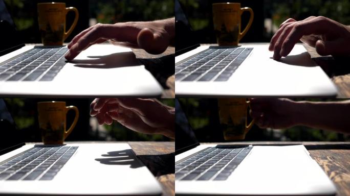 男性手指在笔记本电脑的触摸板上触摸和滑动。在大自然中使用pc的创意自由职业者。面目全非的人在户外工作