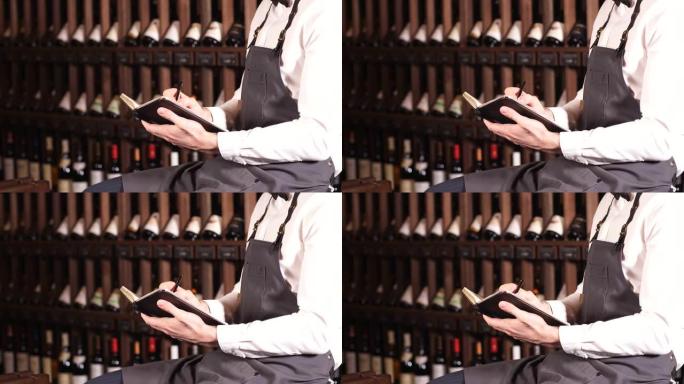 男性葡萄酒管家在葡萄酒商店里看着几瓶酒并在笔记本上写字