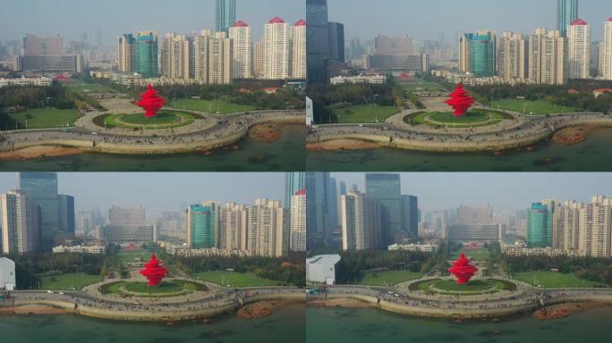 飞越青岛市阳光明媚的傍晚步行湾红色纪念碑交通广场空中俯冲全景4k中国