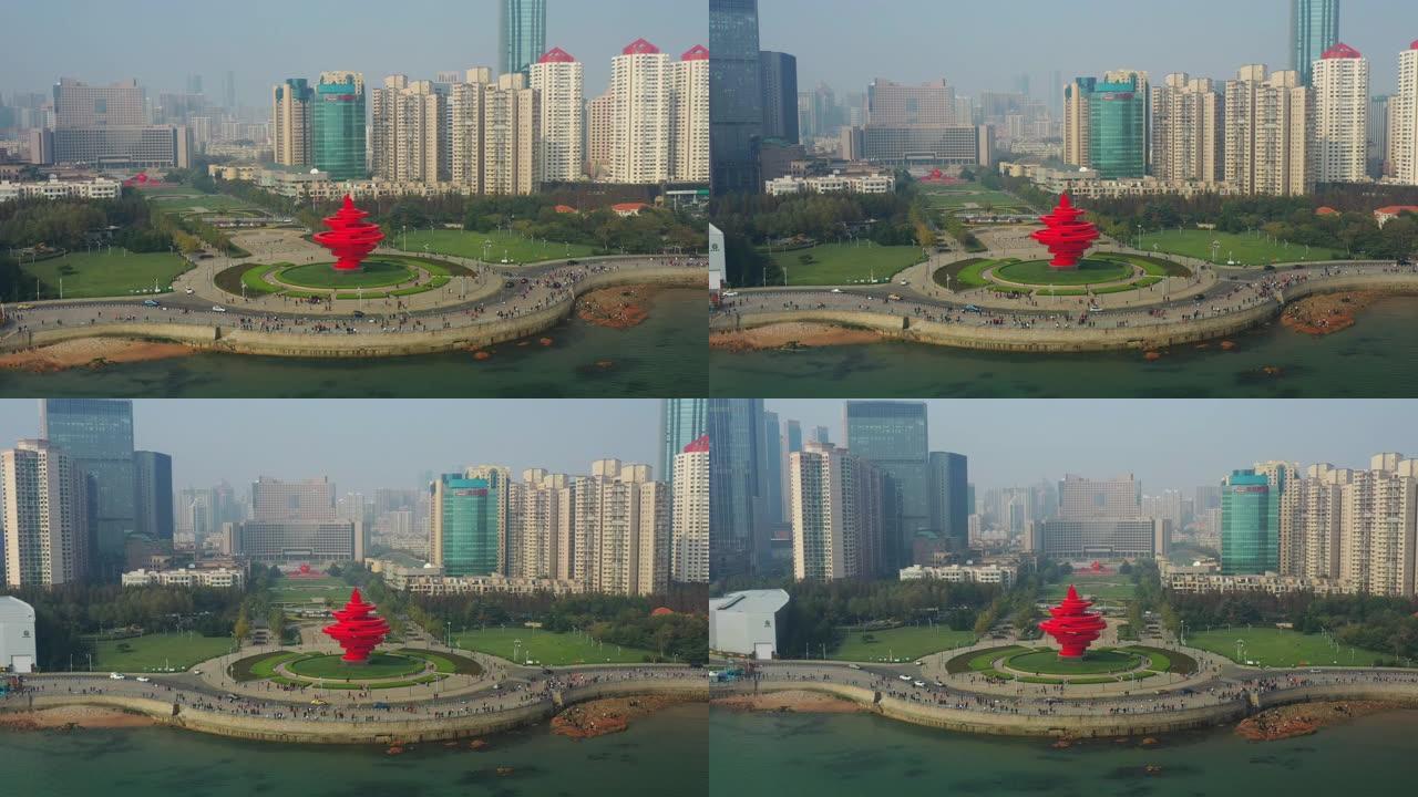 飞越青岛市阳光明媚的傍晚步行湾红色纪念碑交通广场空中俯冲全景4k中国