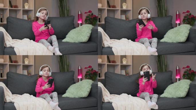 戴着蓝牙耳机的小女孩用智能手机上的mp3播放器欣赏音乐，跟着她最喜欢的歌唱歌，一边在沙发上放松一边摇