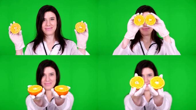 年轻女医生的肖像，营养师身着白色医用服，带着听诊器，手里拿着两半橘子，面带微笑。绿色背景