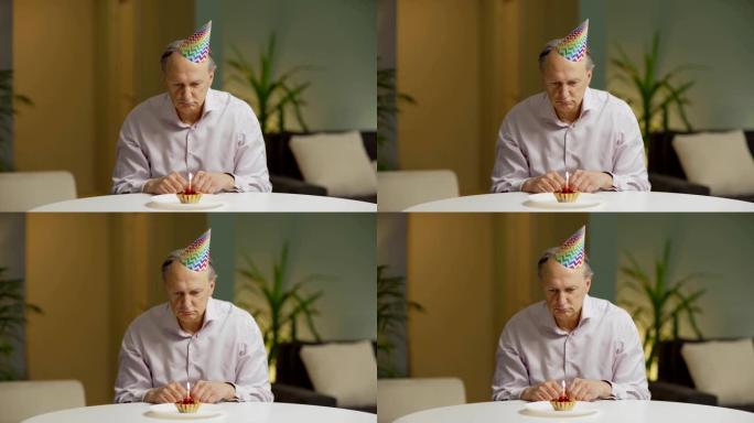 Unhappy senior man in party hat sitting alone at t
