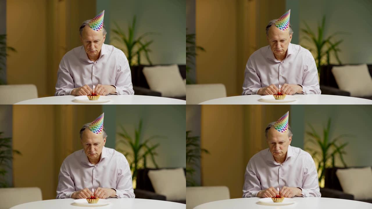 Unhappy senior man in party hat sitting alone at t