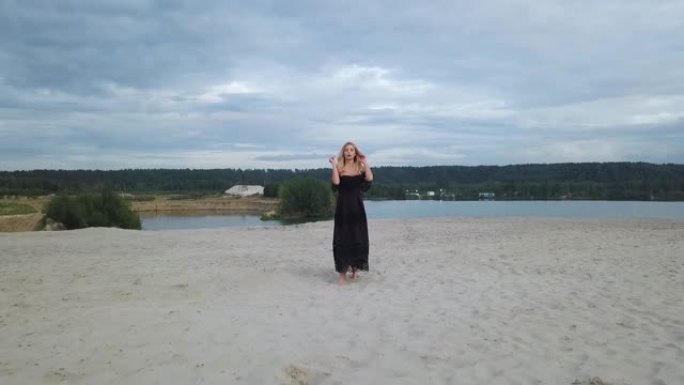 沙滩上穿着黑色连衣裙的金发女人